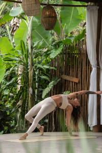 a woman doing a yoga pose in front of plants at Odoyá Casa Hotel in Paraty