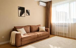 a brown couch in a living room with a window at Ауельбекова 120 in Kokshetau