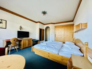 a bedroom with a bed and a desk and a television at Residenz am Park in Sankt Johann in Tirol