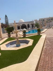 a courtyard with a fountain and a swimming pool at Résidence Djerba Oasis in Mezraya