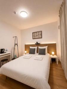 a bedroom with a large white bed with two pillows at Hotel de la gare in Pantin