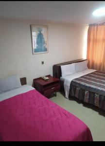 two beds in a hotel room with pink sheets at Hotel Cristals Centro Bogota Estacion las Nieves Calle 18 numero 10 65 in Estación El Salto