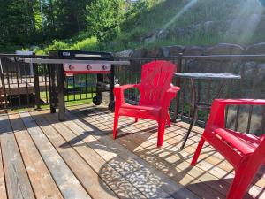 a grill and two chairs and a table on a deck at Chalet Essentiel 76 in Saint-Faustin