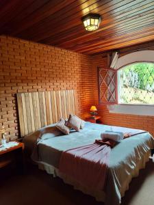 a bedroom with a large bed in a brick wall at Refugio maná in Campos do Jordão