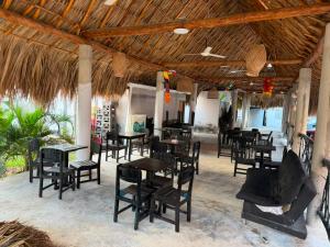 a restaurant with tables and chairs and a straw roof at Hotel Casa Molina in Coveñitas