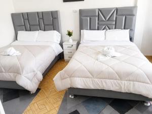 two beds with white sheets and a teddy bear on them at Villa Garden in Ica