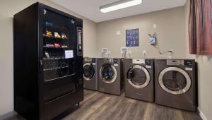 a laundry room with three washing machines and a refrigerator at Magnuson Hotel Extended Stay Canton Ohio in Lake Cable