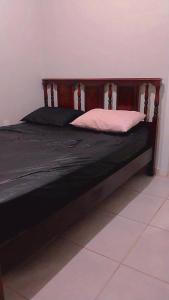 a bed with a wooden frame with a white pillow at Casa Aconchegante S8km do parque do peão in Barretos