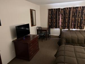 a bedroom with a bed and a dresser with a television at Minnedosa Inn in Minnedosa