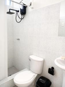 a white bathroom with a toilet and a sink at Villa Garden in Ica
