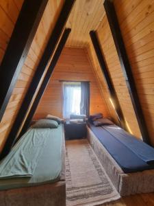 two beds in a attic room with a window at Villa Leos in Ferizaj