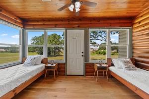two beds in a room with windows and a ceiling fan at Cedar Nest - Lakefront Cabin Retreat in Madill