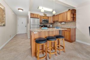 a kitchen with wooden cabinets and bar stools at Kihei Akahi D-104 in Wailea