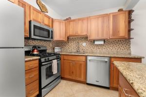 a kitchen with wooden cabinets and stainless steel appliances at Kihei Akahi D-104 in Wailea