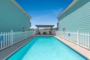 a swimming pool next to a house with a white fence at M & S Turtle Cove in Port Aransas