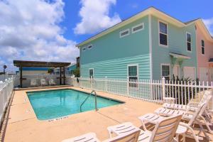 a swimming pool with chairs and a house at M & S Turtle Cove in Port Aransas