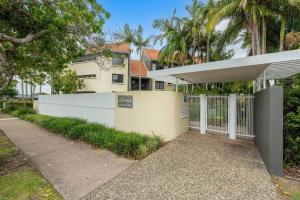 a fence in front of a house with palm trees at Coolum Beach Retreat in Coolum Beach