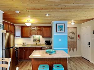 a kitchen with wooden cabinets and a kitchen island with blue seats at My Happy Place in Mustang Beach