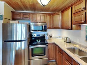 a kitchen with wooden cabinets and a stainless steel refrigerator at My Happy Place in Mustang Beach