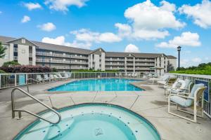 a swimming pool with chairs and a building at Rock-a-While Whispering Pines 214 in Pigeon Forge