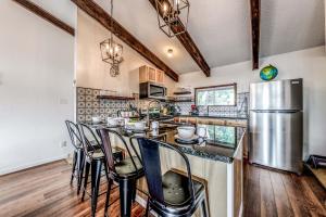 a kitchen with a bar with chairs and a refrigerator at Hold Your Horses in Ruidoso +22 photos
