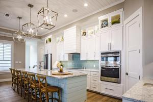 a kitchen with white cabinets and a blue island at The Sanctuary in Padre Island