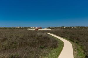 a path through a field with a blue sky at On the Half Shell in Port Aransas