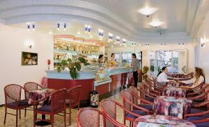 a restaurant with tables and chairs and a bar at Hotel Miramare in Bibione