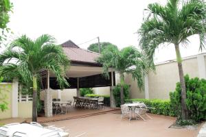un patio con mesas, sillas y palmeras en KSF Place Alaka, en Lagos