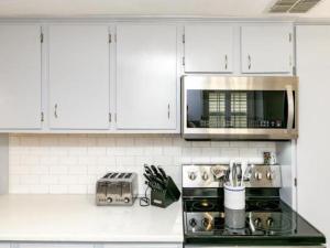 a white kitchen with a stove and a microwave at Cape Cod Cottage in Port Aransas
