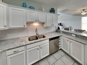 a kitchen with white cabinets and a sink at Sandy Starfish in Port Aransas +29 photos