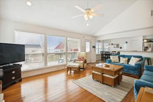 a living room with a blue couch and a tv at Pelican Path in Galveston