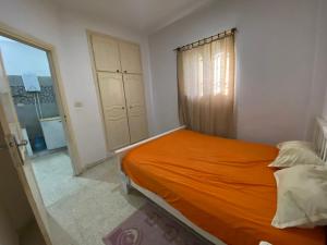 an orange bed in a small room with a window at Raies in Akouda +35 photos
