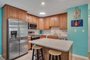a kitchen with a stainless steel refrigerator and wooden cabinets at Pawsitively Paradise in Mustang Beach +24 photos