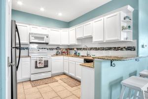 a kitchen with white cabinets and blue walls at Sandbar in Port Aransas