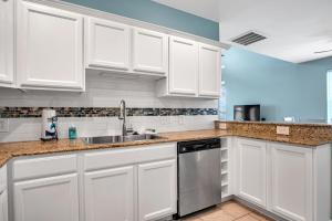 a kitchen with white cabinets and a sink at Sandbar in Port Aransas