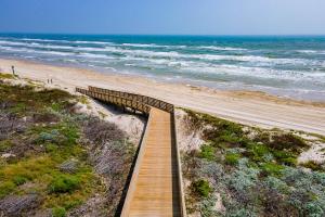 a wooden boardwalk leading to a beach with the ocean at Beach-A-Holic in Padre Island