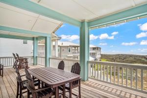a porch with a wooden table and chairs on a deck at Beach-A-Holic in Padre Island