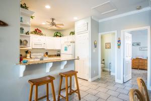 a kitchen with white cabinets and two stools at 3 Sheets To the Zin in Port Aransas +21 photos