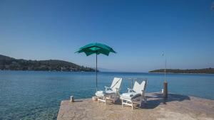 a group of chairs and an umbrella on the water at House Victoria in Lovište