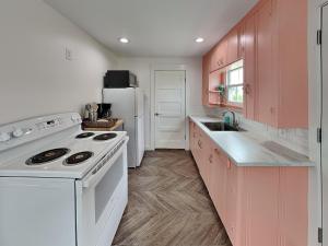 a kitchen with pink cabinets and a white stove top oven at Coral Cottage in Rockport