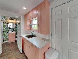 a kitchen with pink cabinets and a sink at Coral Cottage in Rockport