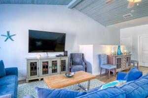 a living room with a blue couch and a tv at Flip Flops & Pop Tops in Port Aransas