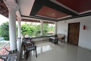 a living room with chairs and a balcony at Wayanad Palm Grove Retreat 1st Floor in Wayanad