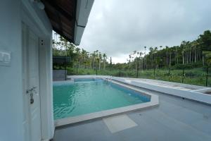 a swimming pool in the side of a house at Wayanad Palm Grove Retreat 1st Floor in Wayanad