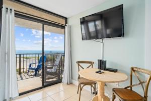 a living room with a table and a television and a balcony at Laguna Reef #308 - Beautiful Bay View in Rockport