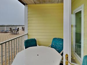 a porch with a white table and chairs on the beach at Port A Condo in Port Aransas