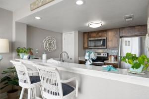 a kitchen with a counter and two white chairs at Laguna Reef #213 - Four Point Lighthouse in Rockport