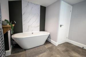 a white bath tub in a bathroom with a marble wall at The Nook in Claypits
