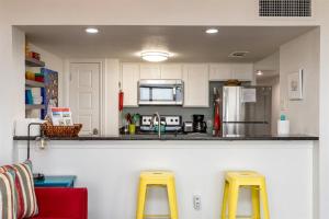 a kitchen with two yellow stools in front of a counter at Laguna Reef #215 - Tequila Sunrise in Rockport +33 photos